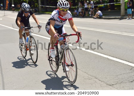 PLOIESTI-BUCHAREST - JULY, 05: Two beautiful women riding bicycles in a sunny day, competing for Road Grand Prix event, a high-speed circuit race, July 05, 2014 in Ploiesti-Bucharest, Romania