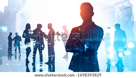 Silhouette of confident businessman standing with crossed arms in abstract city with double exposure of his blurry business team. Concept of leadership. Toned image