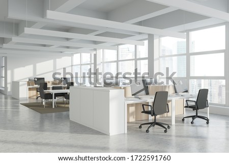 Corner of modern Industrial style open space office with white walls, concrete floor, rows of computer tables and panoramic windows with blurry cityscape. 3d rendering