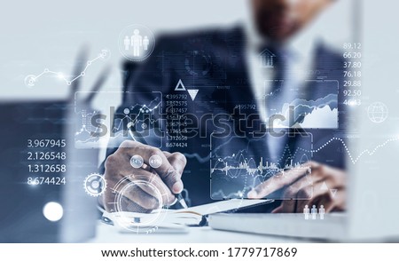Serious African American businessman working in blurry office with double exposure of HUD infographic interface. Concept of statistics and data analysis. Toned image