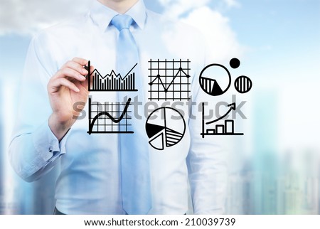 Young businessman drawing a set of the graphs including pie chart, line graph and sketches in a glass screen.