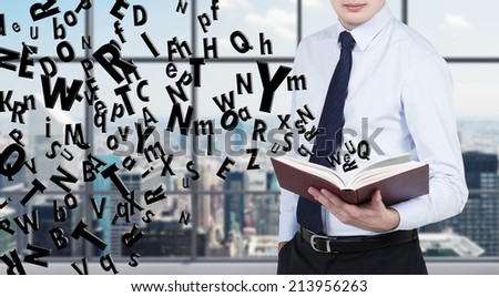Businessman is reading a book with flying letters. Panoramic office background.