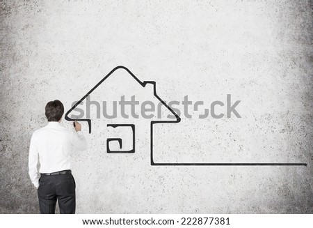 Young professional drawing a concept of real estate market. Concrete background.