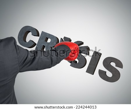 Boxing glove punching the word \'crisis\'. A metaphor of to deal with crisis.