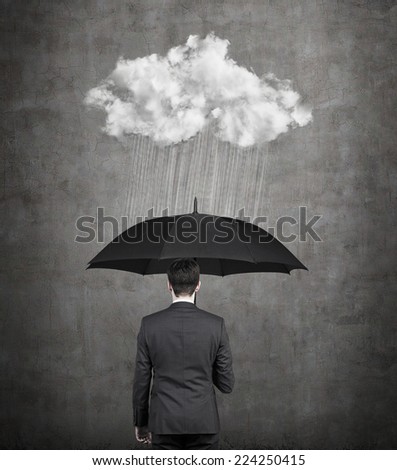 Businessman with umbrella protecting himself from the storm. A concept of protection from recession or economic crisis.