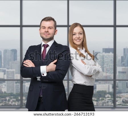 A young business couple are standing in a modern office. New York cityscape.