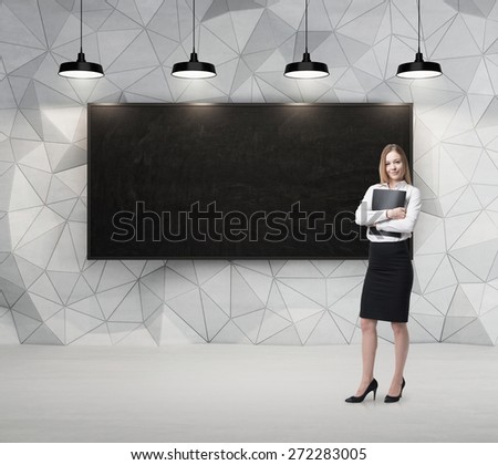 Young beautiful business lady is holding a black document case. Blank blackboard on the background.