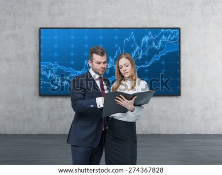A young business couple are looking at the black document case in a modern office. A concept of the teamwork. forex screen background.