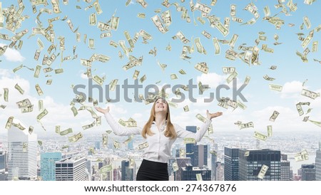 Beautiful blonde business woman is happy about falling dollar notes from the sky. New York city background.