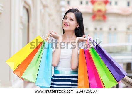 A happy smiling lady with a lot of colourful shopping bags from the fancy shops. Luxury shopping venue.
