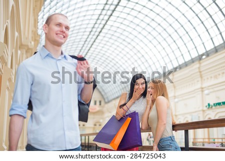 Smiling girls and a man with shopping bags in a luxury central shop. Shopping, sale, gifts and holidays concepts. High-street shopping.