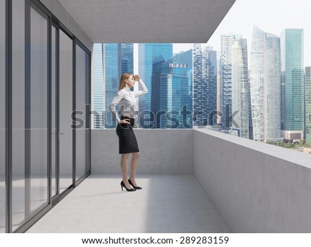 Young business lady is standing on the balcony of the skyscraper and looking at the new business perspectives. Singapore panoramic view.