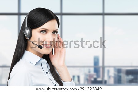 Portrait of smiling cheerful support phone operator in headset. New York panoramic office background.