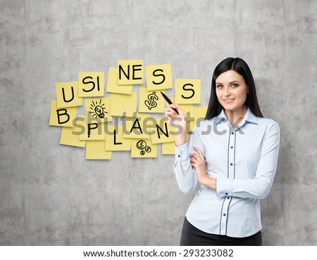 Brunette lade shows the new business plan. Yellow stickers are hanged on the concrete wall.