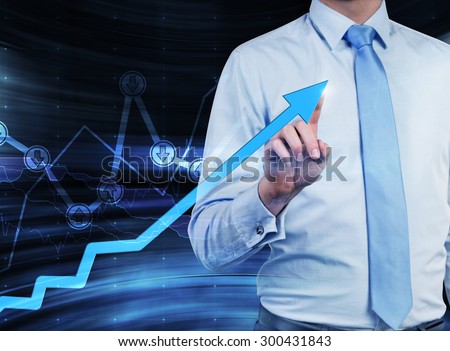 Close-up of the businessman who points out the growing arrow, which symbolises the concept of the success. A graph with drawn arrow signs \'buy\' or \'sell\' on the background.