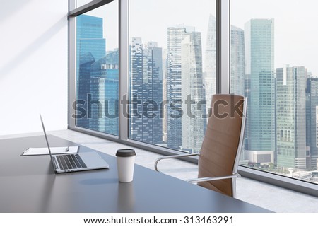 A workplace in a modern panoramic office with Singapore view. A grey table, brown leather chair. Laptop, writing pad for notes and a cap of coffee are on the table. Office interior. 3D rendering.
