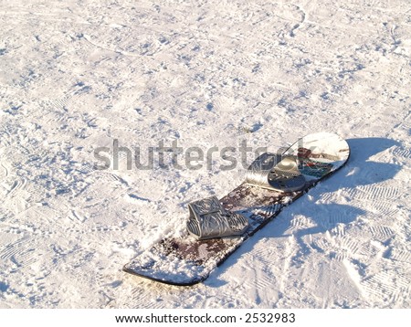 snowboard sitting alone in snow that has been packed down