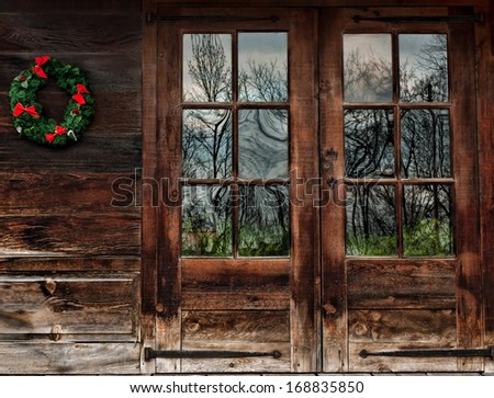 doors of a rustic wood cabin with christmas wreath