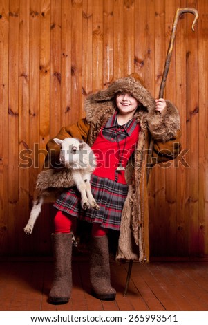 Playful girl shepherd with his staff under his arm a lamb on the farm