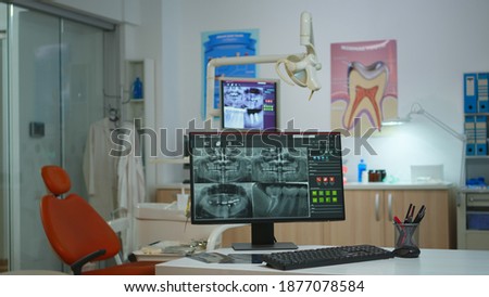 Interior of modern dentistry medical room with special stomatologial equipment. Stomatology clinic with nobody in prepared for next patient with radiograph displayed on computer screen Stockfoto © 