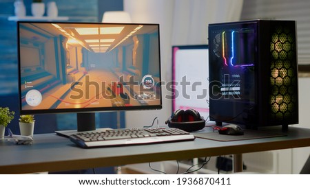 Professsional gaming empty room studio with neon lights and RGB powerful computer, keyboard and mouse. FPS shooter video game on pc display, stream chat on television