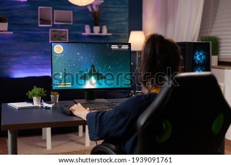 Focused player sitting on gaming chair in home studio and playing online videogames using RGB keyword. Professional pro player streaming online video game new graphics using powerful computer