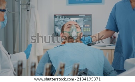 Patient with oxygen mask receiving anesthesic in dentistry cabinet, getting ready for stomatological procedure with dental tools and drill to polish caries. Oral care anesthesia on man. Stock foto © 