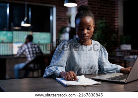 Finance company sales representant reviewing market trend documentation while sitting at desk in office at night. Forex stock agent analyzing financial charts while looking at paperwork clipboard. Stock fotó © 