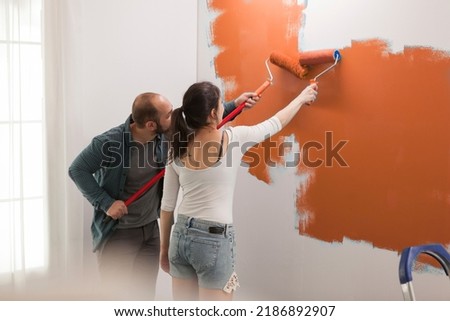 Family using orange color paint on walls to redecorate apartment room during interior design renovation. Doing housework redecoration with painting tools, ladder and diy equipment. Imagine de stoc © 