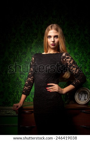 Gorgeous woman in green vintage room in black dress. Old styled retro vintage green patter. Girl is in rich exclusive interior. Sensuality and sexy. Glamour and fashion
