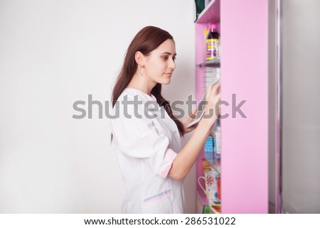 Pharmacist girl smiling with digital tablet in hands at the counter desk
