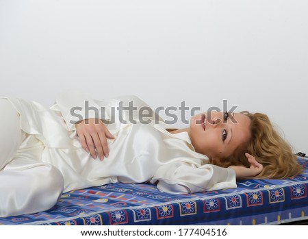 Young woman-girl in pyjamas smiling happy and serene lying on the soft mattress of his bed