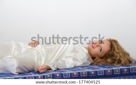 Young woman-girl in pyjamas smiling happy and serene lying on the soft mattress of his bed