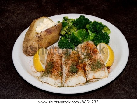 Baked Cod Dinner broccoli potato lemon on black background