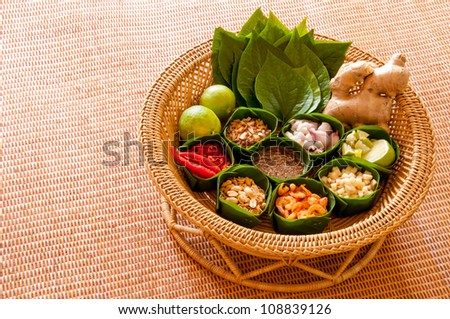 Miang Kham is a tasty snack often sold as Thailand street food. It involves wrapping little tidbits of several items in a leaf, along with a sweet-and-salty sauce. - stock photo