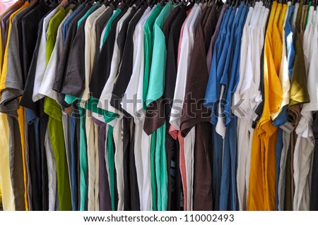 Variety of man\'s shirts on hangers at street market.
