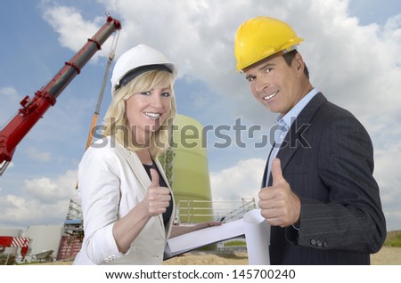 Male and female architect and construction site smiling and thumb up, outdoor