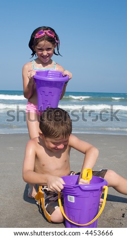 Devious sister sneaks up on brother and dumps a bucket of water on his head.