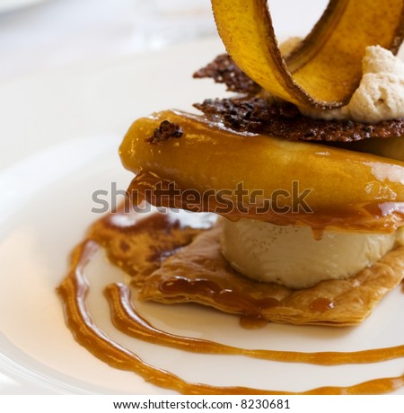 A decadent dessert of sliced banana, caramel, and cinnamon.  Vanilla ice cream is sandwiched in the middle, with a crispy banana slice on top.