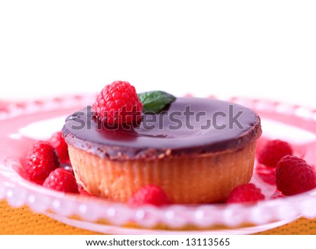 A gourmet chocolate raspberry tart dessert on glass dish.