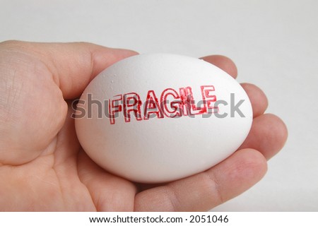 Hand holding a white egg that is stamped \
