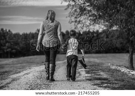 Two Out of Three: A mother and son walk together hand in hand. The little boy holds the hat of his father, who was killed in the line of duty.