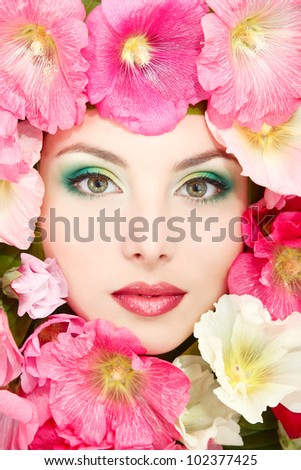 beauty portrait of beautiful female face with pink, red and white mallow flowers frame
