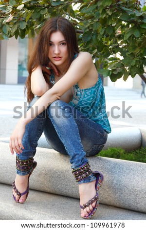 Outdoors street portrait of beautiful young brunette girl near tree