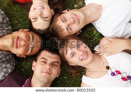 students faces happy friends group lying on green grass