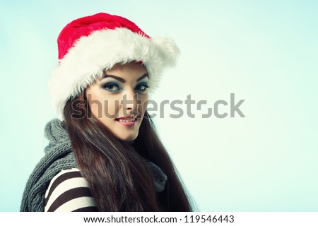 happy smiling christmas woman in santa\'s red hat, winter girl over blue background