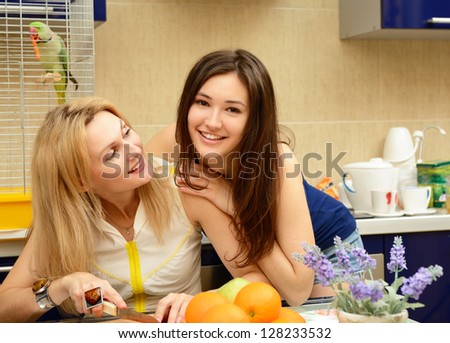 Mother with her daughter teenager peel and cut vegetables together in kitchen at home