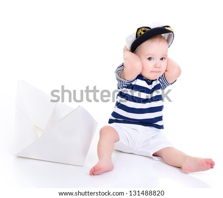 cute baby boy sitting in captain cap with ship of paper - sailor in future, over white background