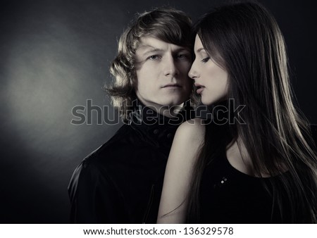 Sexy passion couple, beautiful young woman and man in love posing in studio, over black