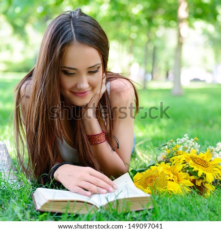 beautiful cheerful girl reading book in the summer park